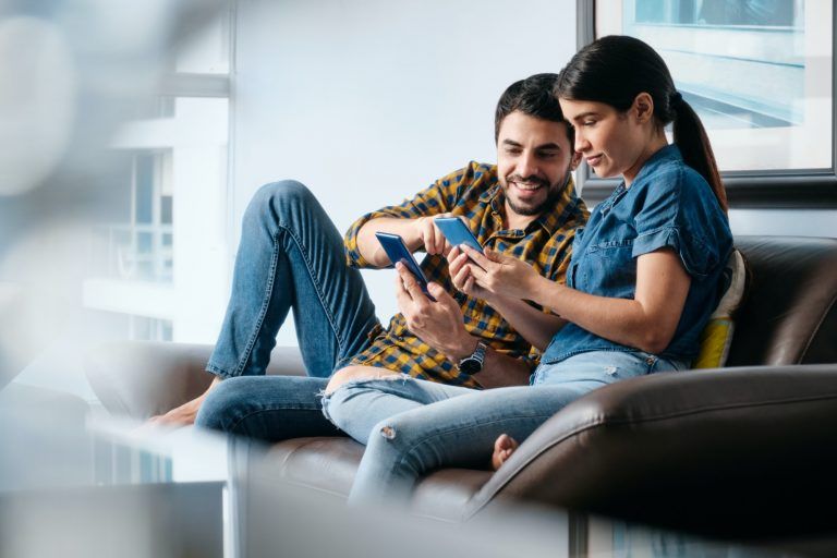 Young Man Helping Girlfriend With Phone App at Home